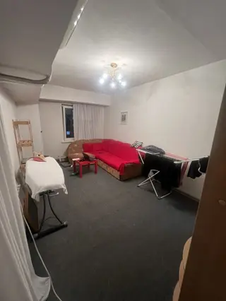 Просторная жилая комната с окном и потолочным светильником. Светлые